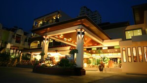 A hotel with a covered outdoor area, multiple floors, and a well-lit entrance. - Karon Sea Sands Resort (Karon)