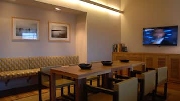 A dining area with a wooden table and chairs, a bench, and framed pictures on the wall.