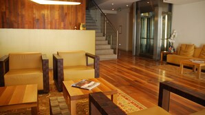 Un vestíbulo moderno con piso de madera, una escalera y una zona de recepción con un sofá y una mesa de centro.