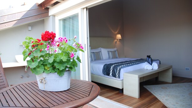 Un dormitorio con cama, mesita de noche y una planta en maceta con flores.