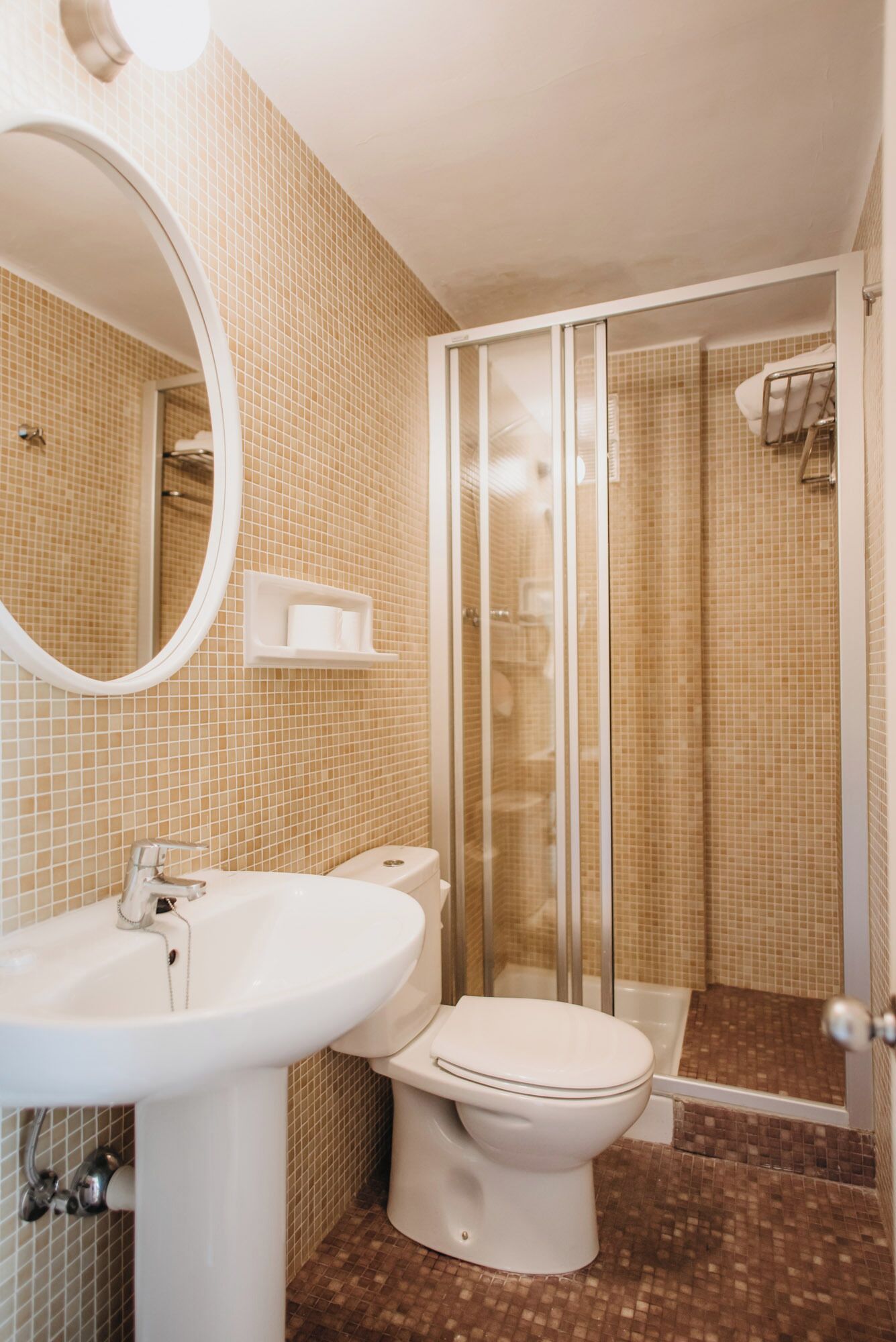 Une salle de bain équipée d’un lavabo, de toilettes et d’une douche à parois de verre.