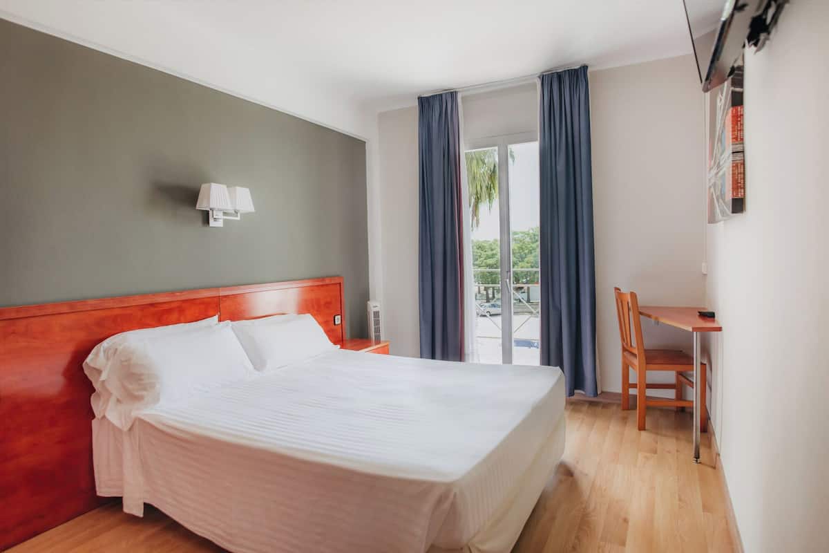 A hotel room with a bed, a desk, and a chair.