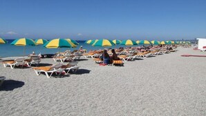 A beach with rows of sun loungers and umbrellas.