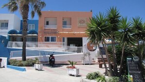 A hotel with a pink facade, a white entrance, and a signboard for a restaurant.