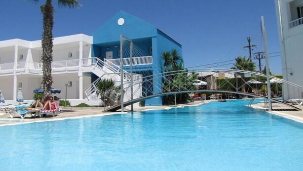 A swimming pool with a white building and a blue structure in the background.