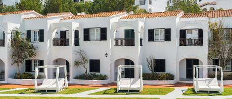 Un edificio blanco con balcones y un jardín con macetas blancas.