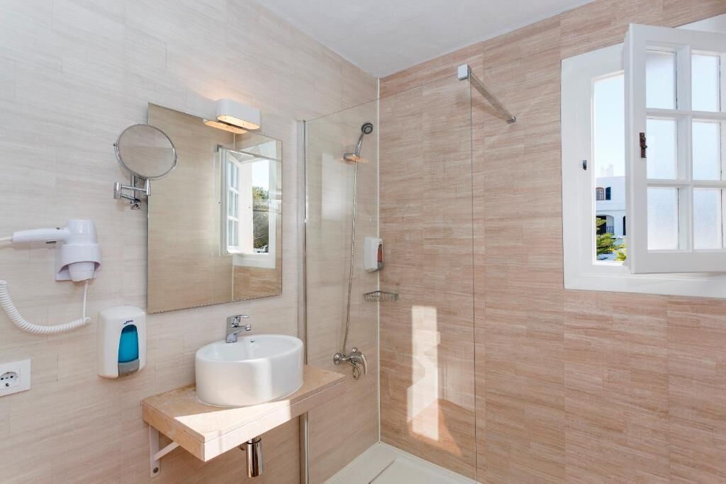 Un baño moderno con lavamanos, espejo y ducha.