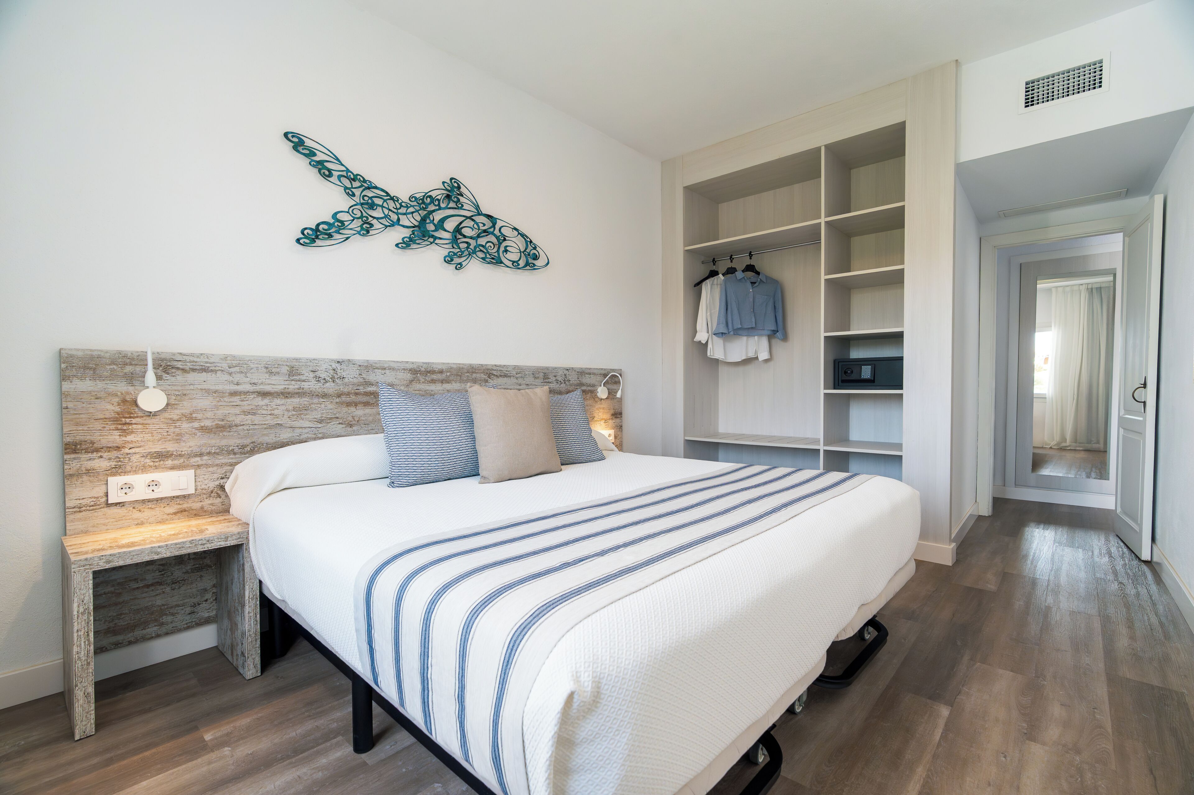 Un dormitorio con cama, mesita de noche, decoración en la pared y vestidor.