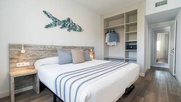 Un dormitorio con cama, mesita de noche, decoración en la pared y vestidor.