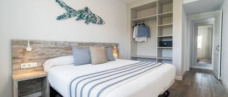 Un dormitorio con cama, mesita de noche, decoración en la pared y vestidor.