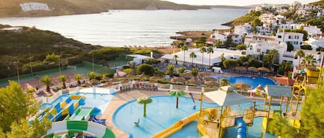 Una piscina al aire libre, sombrillas, sillones reclinables de piscina