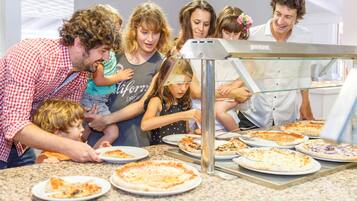 Una familia de siete personas en una estación de pizza, mostrando diferentes tipos de pizza.
