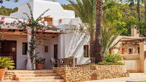A resort with a white building, palm trees, and a pool area with lounge chairs. - Can Lluc Boutique Country Hotel & Villas (Sant Antoni de Portmany)