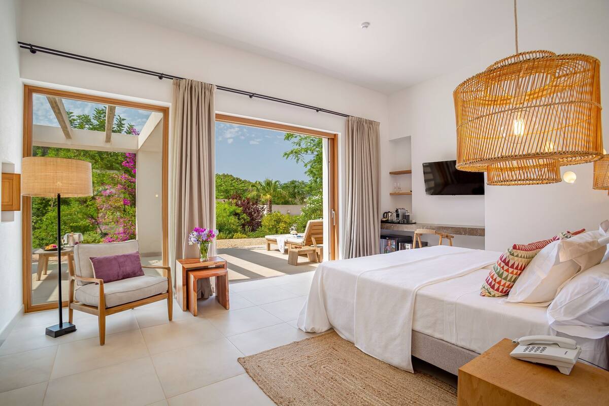 A modern hotel room with a large bed, a sofa, a small table, and a TV.