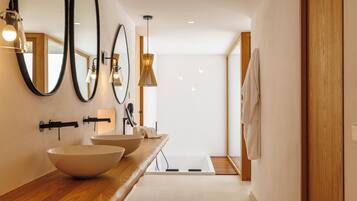 Un baño moderno con un espejo ovalado grande, dos lavamanos y un mueble de tocador de madera.