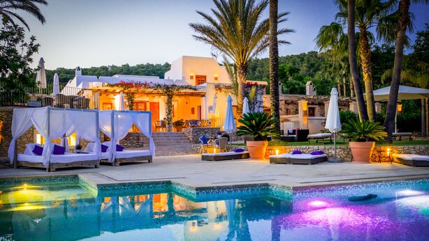 A pool area with lounge chairs and umbrellas, a stone building with a white facade, and palm trees. - Can Lluc Boutique Country Hotel & Villas (Sant Antoni de Portmany)