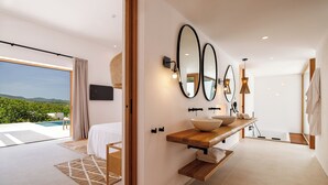 A modern bathroom with a large mirror, a wooden vanity, and a view of a pool and mountains. - Can Lluc Boutique Country Hotel & Villas (Sant Antoni de Portmany)