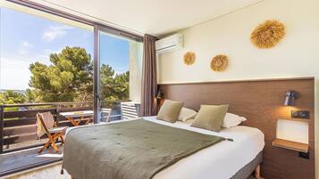 Ein modernes Schlafzimmer mit einem großen Bett, einem Balkon mit Tisch und Stühlen sowie dekorativer Wandgestaltung.