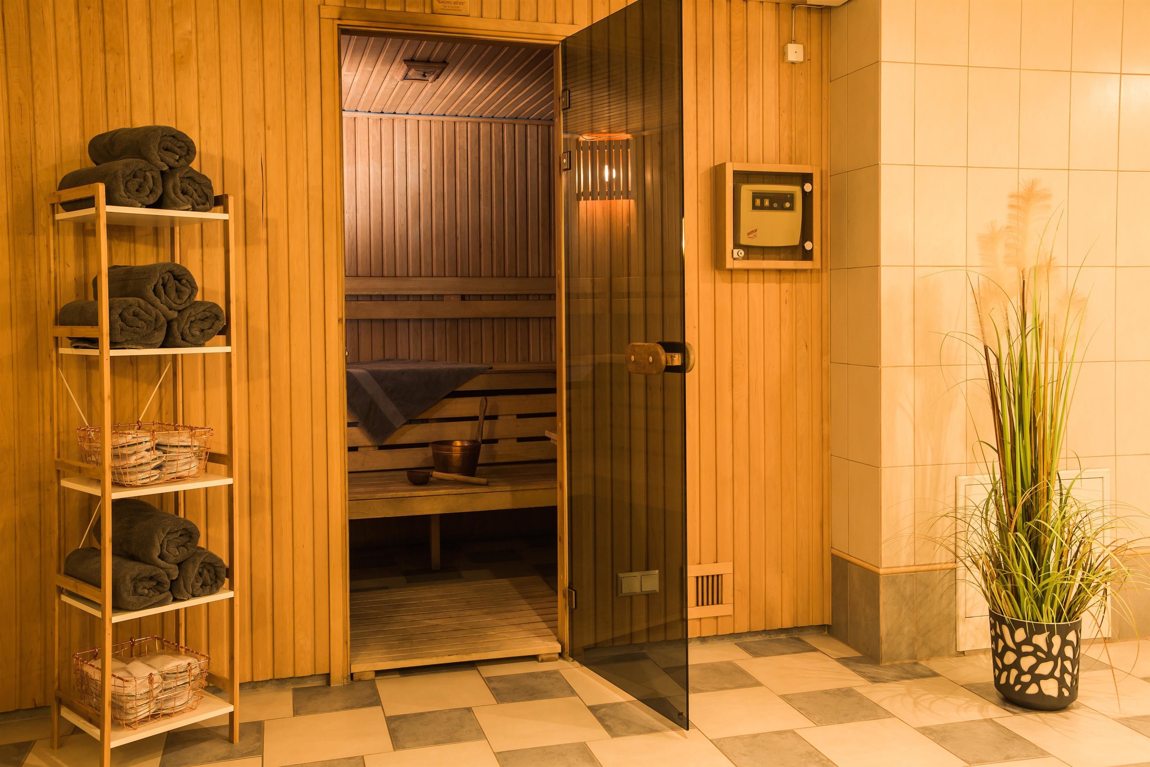A sauna room with wooden walls, a glass door, and a shelf with towels.