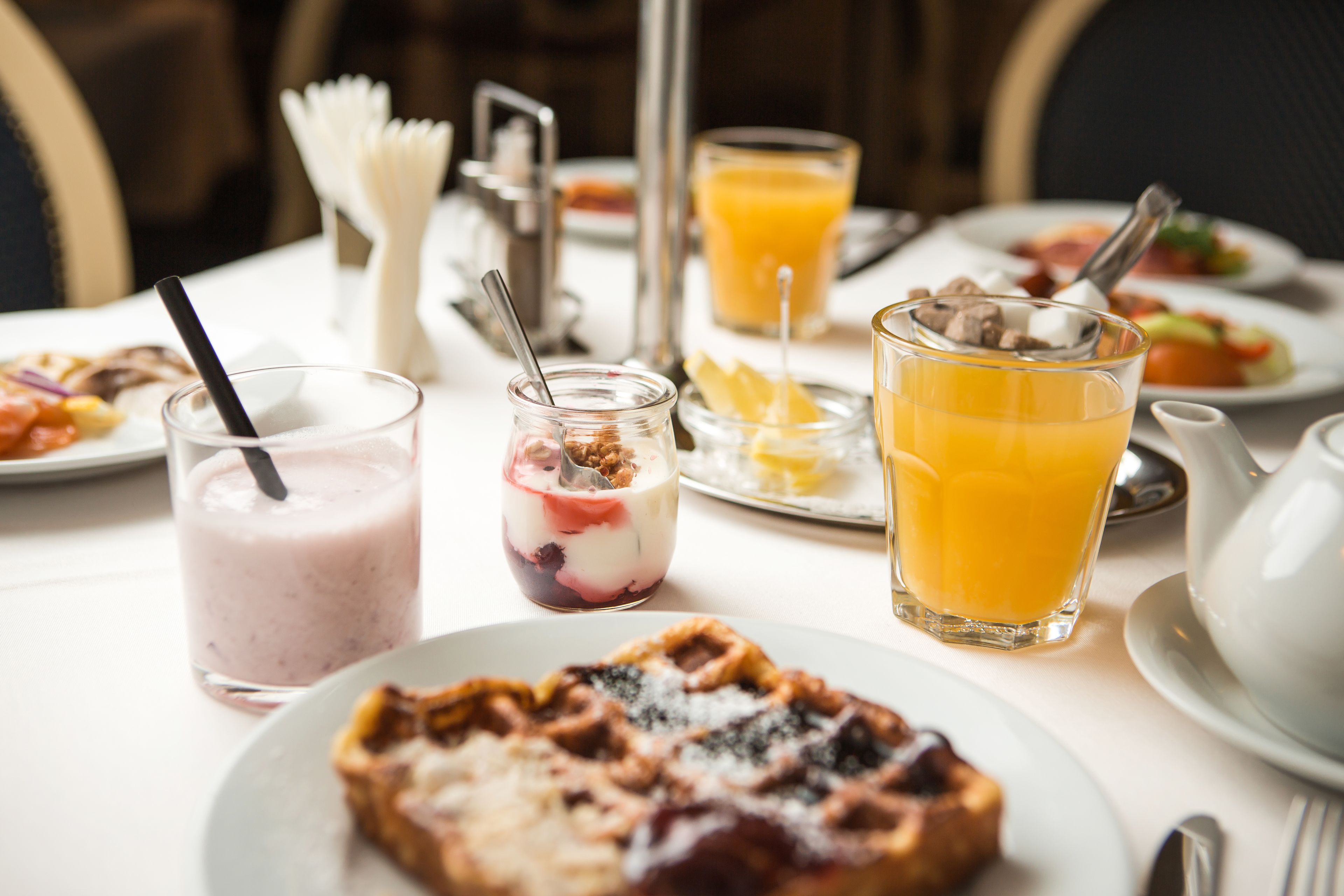 A breakfast setting with waffles, a smoothie, and orange juice on a table.