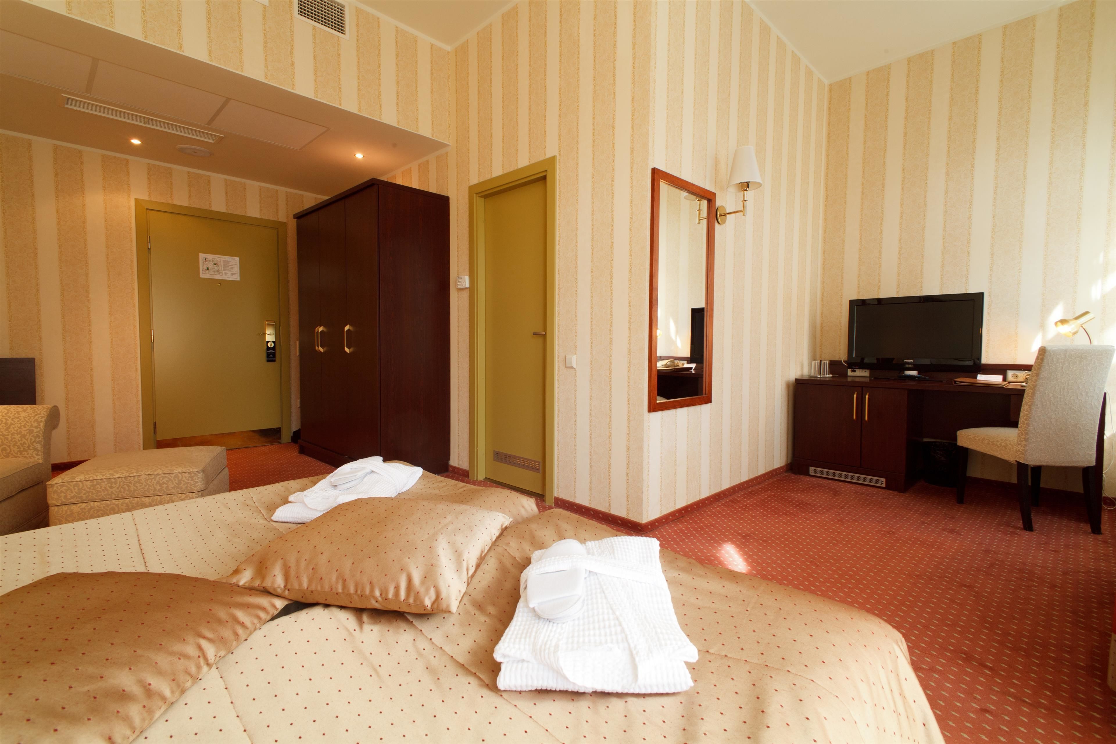 Une chambre d’hôtel avec un lit, un bureau, une télévision et un miroir.