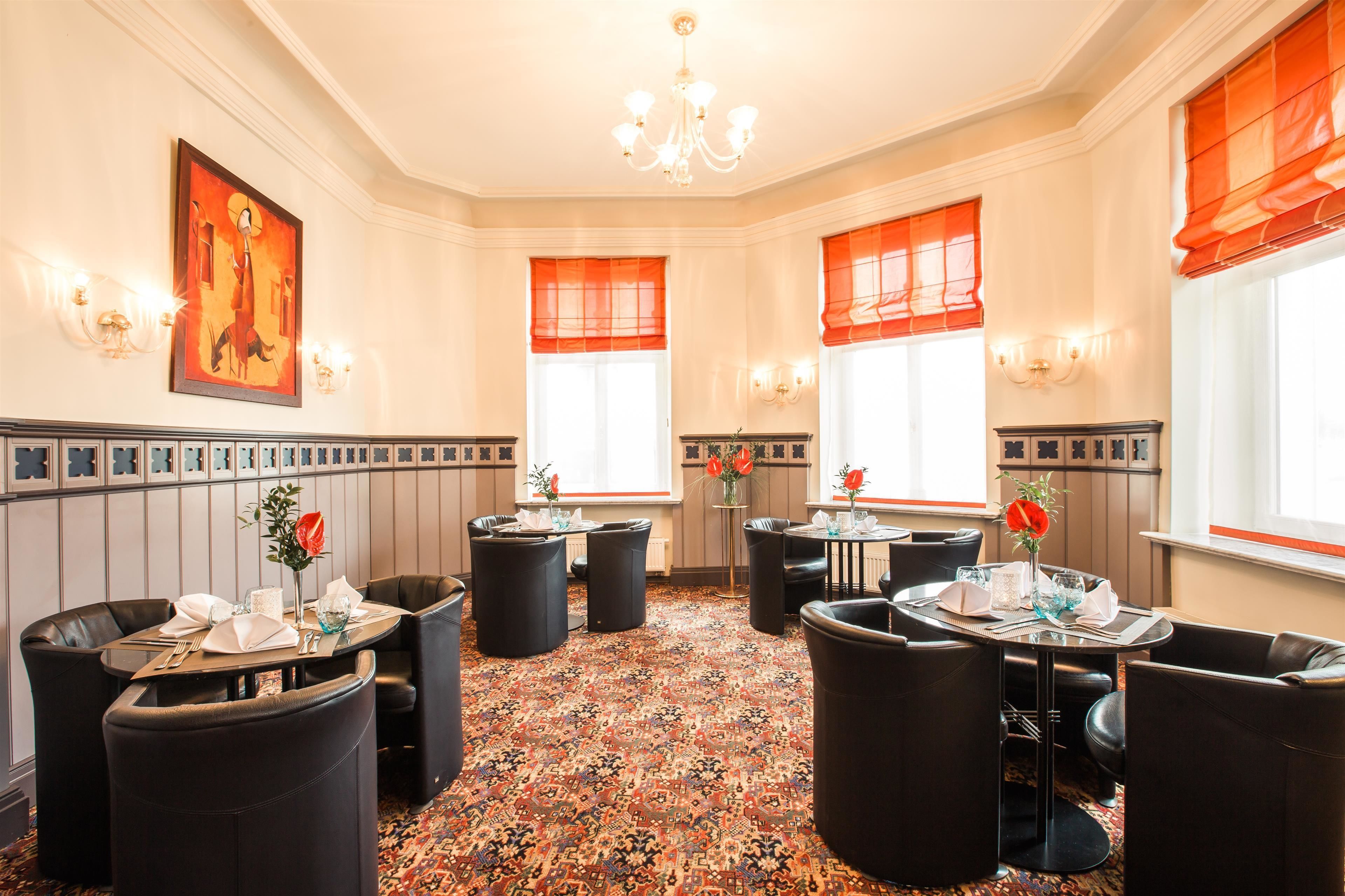 A hotel dining area with round tables, black leather chairs, and a patterned carpet.