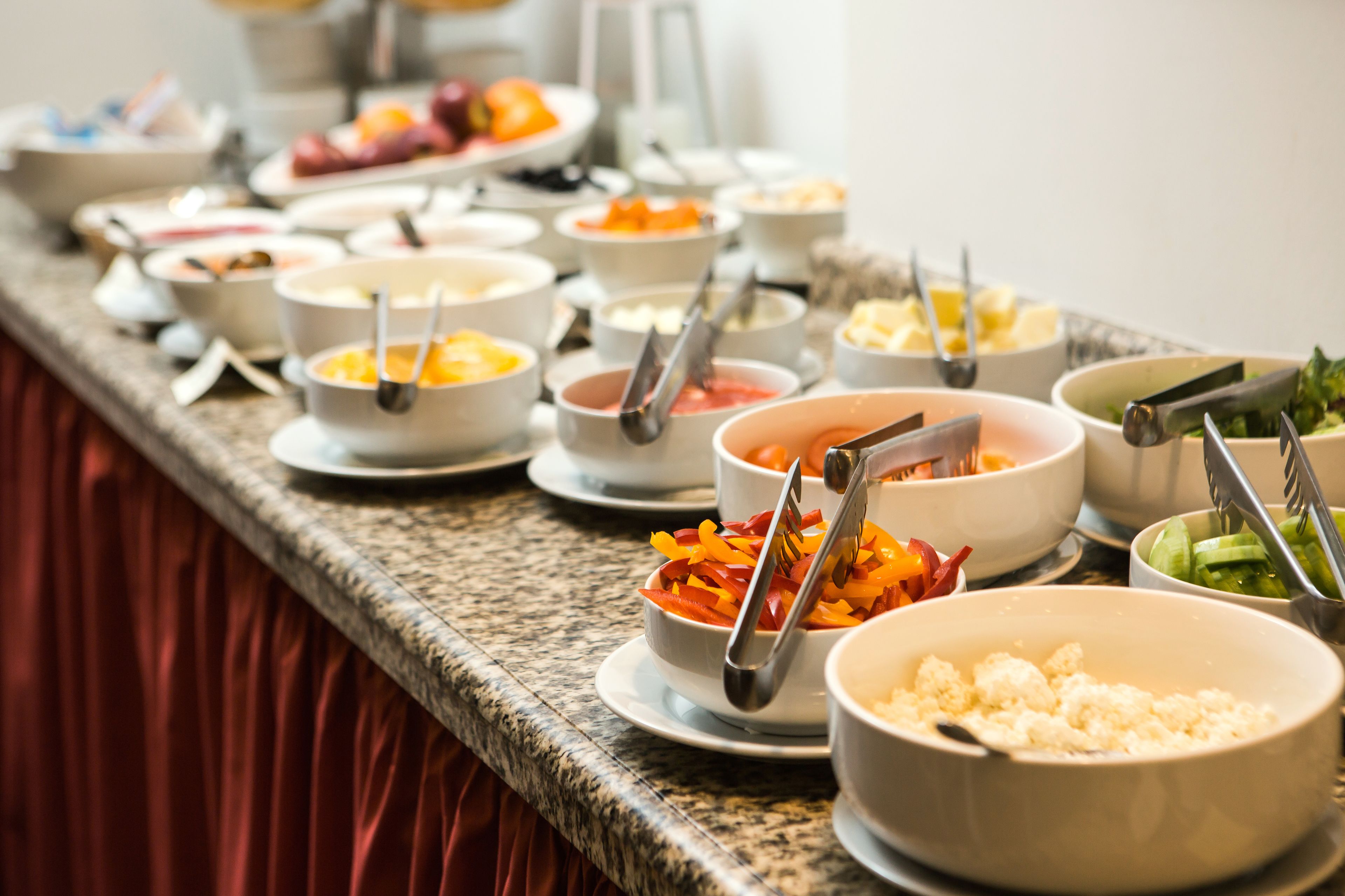 Un bufé con diversos platos, incluyendo verduras, frutas y quesos.