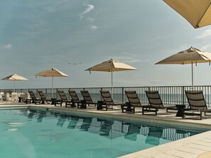 Alberca al aire libre, sombrillas en la alberca y camastros