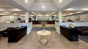 Un amplio vestíbulo con mostrador de recepción, zonas de estar y una escalera que conduce a los pisos superiores.