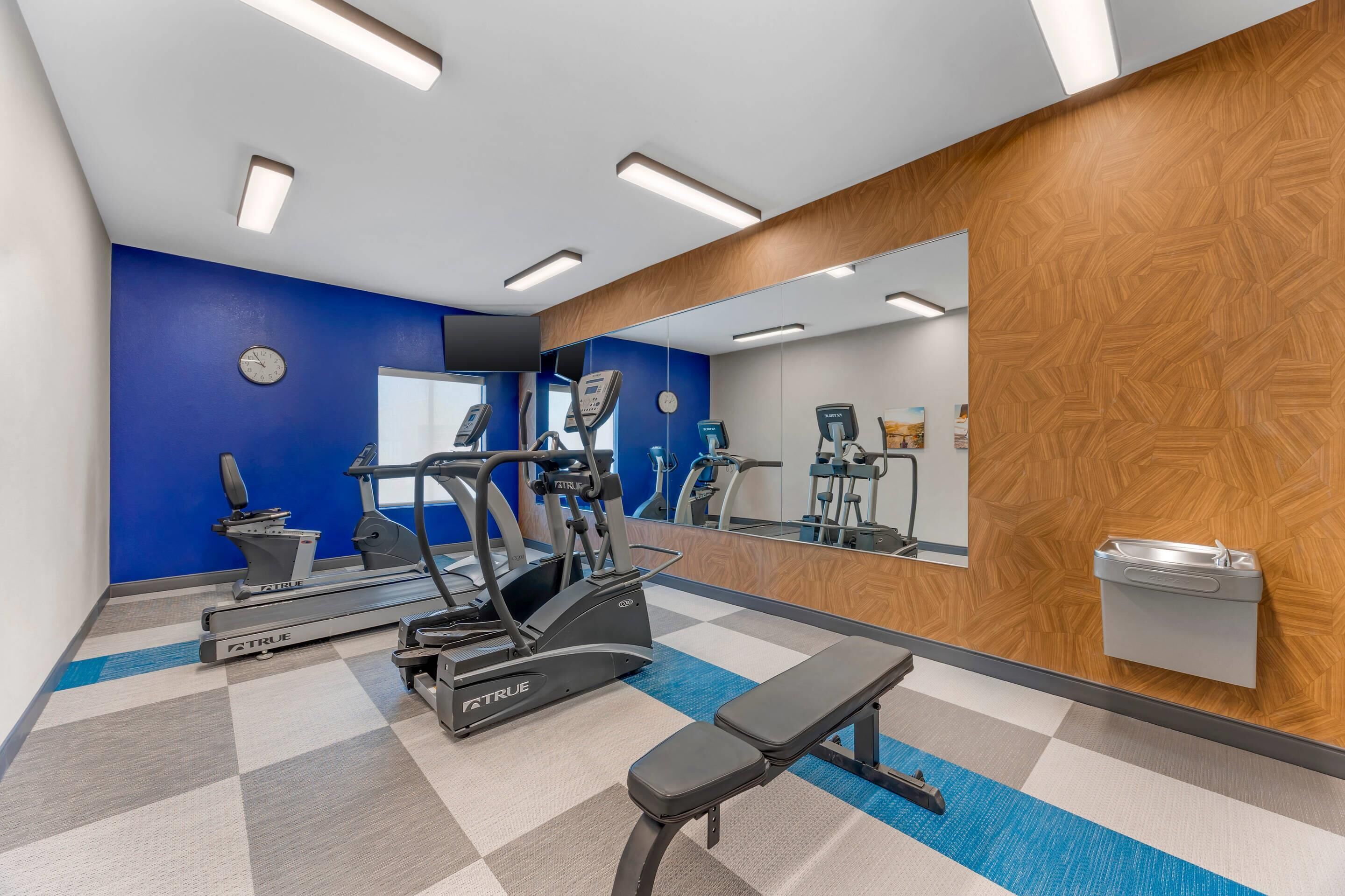 A gym with treadmills, an elliptical, and a bench.