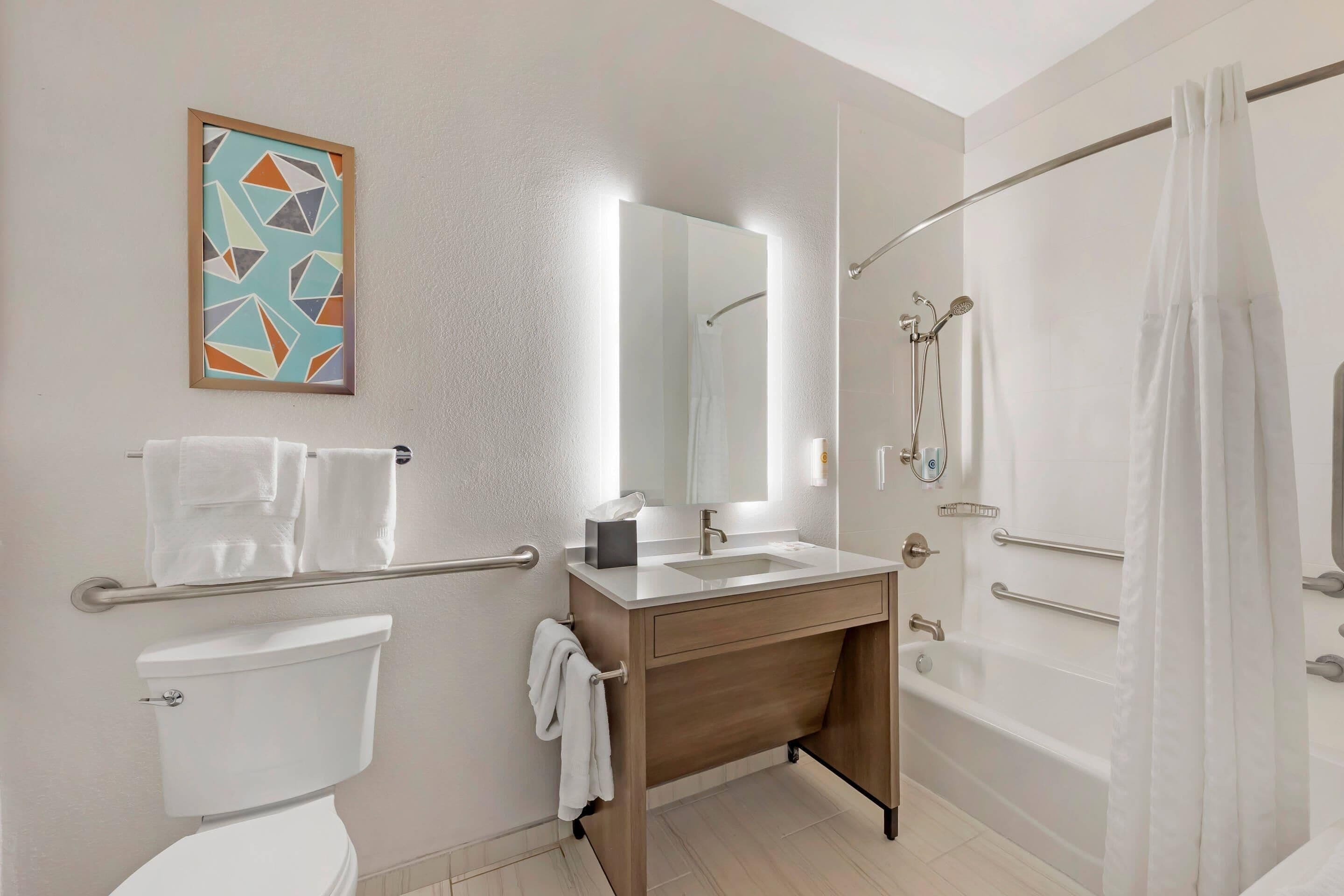 Un bagno moderno con servizi igienici, lavandino, specchio, doccia e portasciugamani.