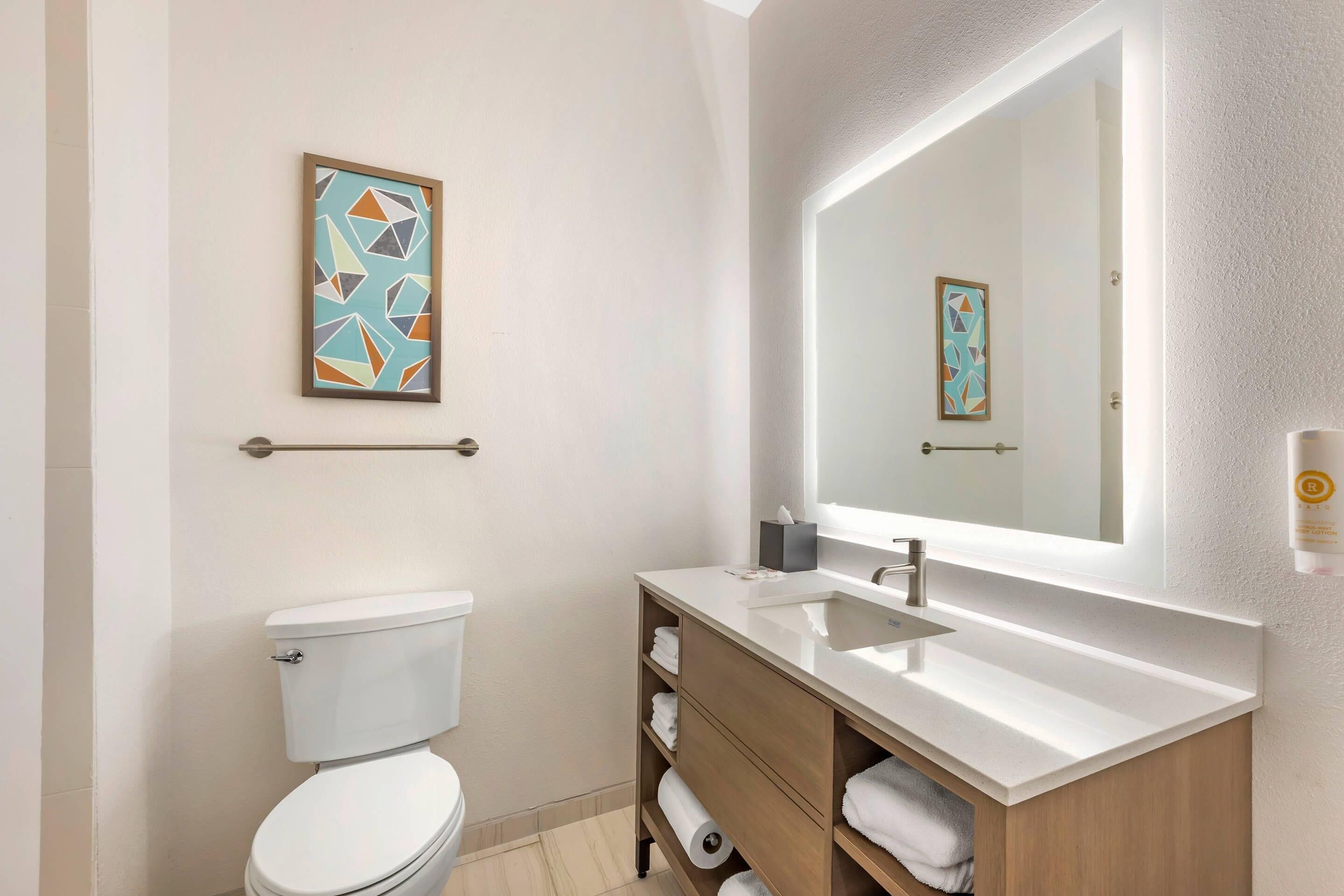 Une salle de bain moderne équipée d’un WC, d’un lavabo, d’un miroir et d’un porte-serviettes.
