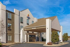 A modern hotel with a clear entrance, a covered waiting area, and a sign indicating a clearance of 11-16 feet.