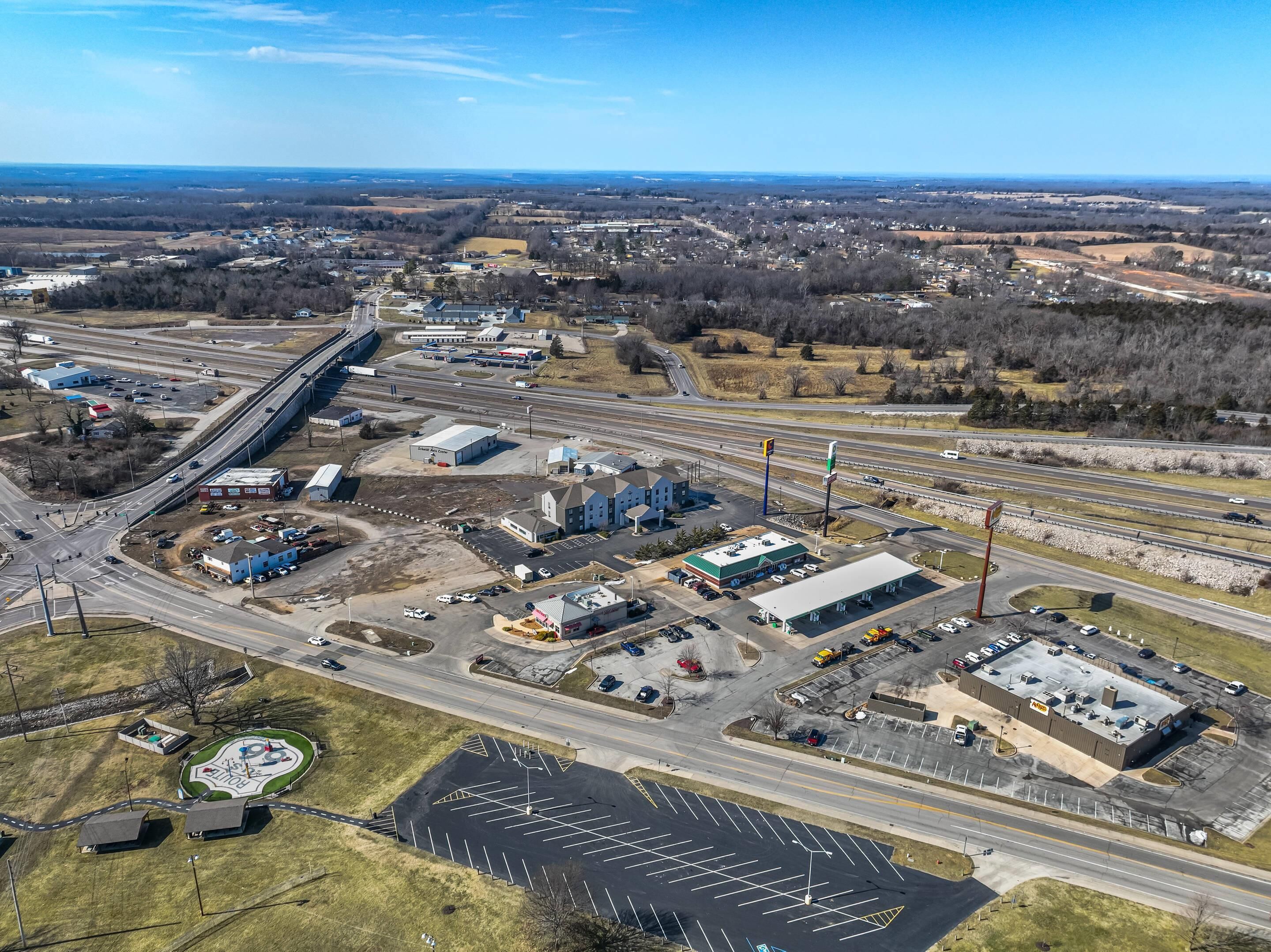 An aerial view of a commercial area with multiple buildings, roads, and parking lots.