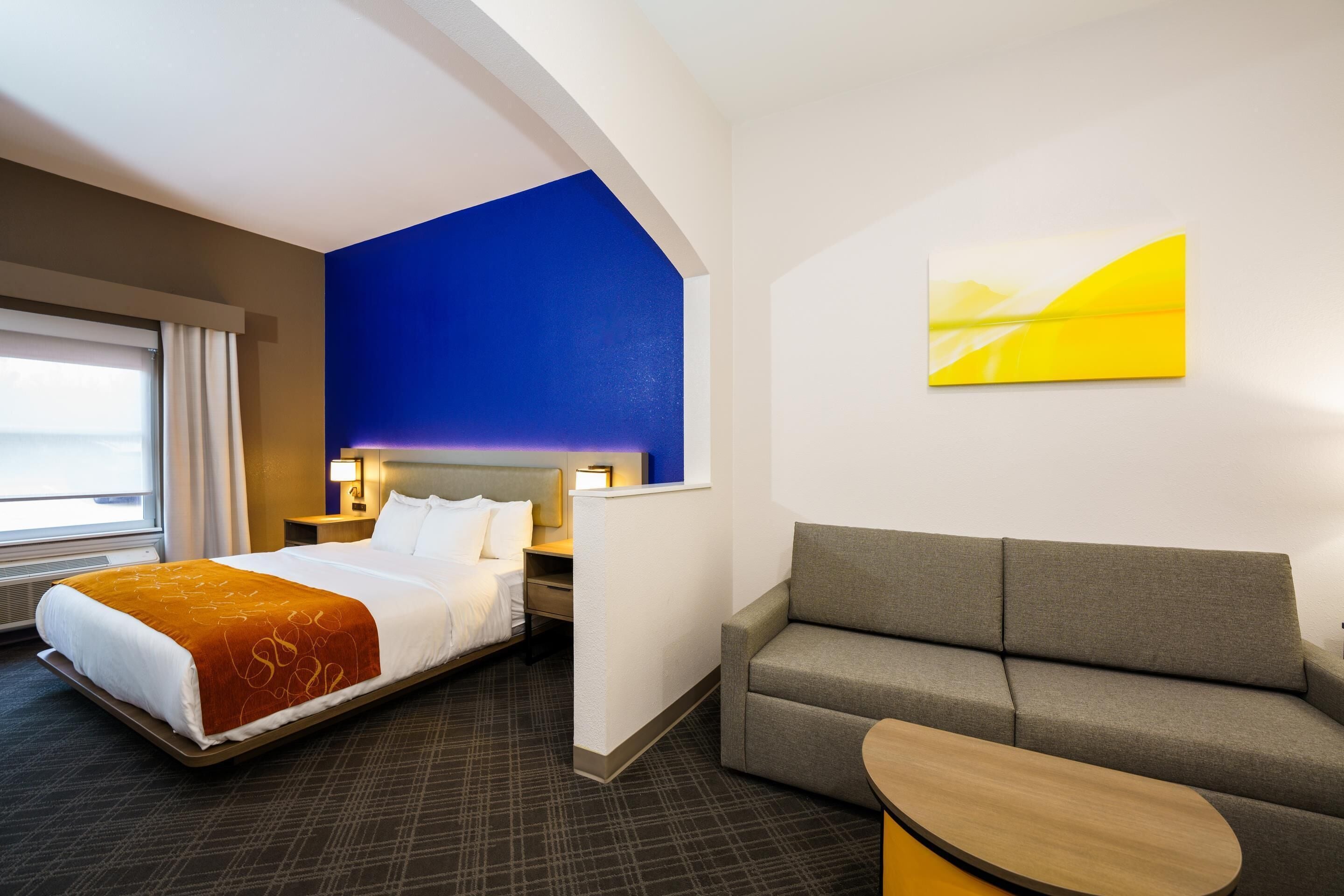 Ein Hotelzimmer mit Bett, einer Couch, einem kleinen Tisch und einem Bild an der Wand.