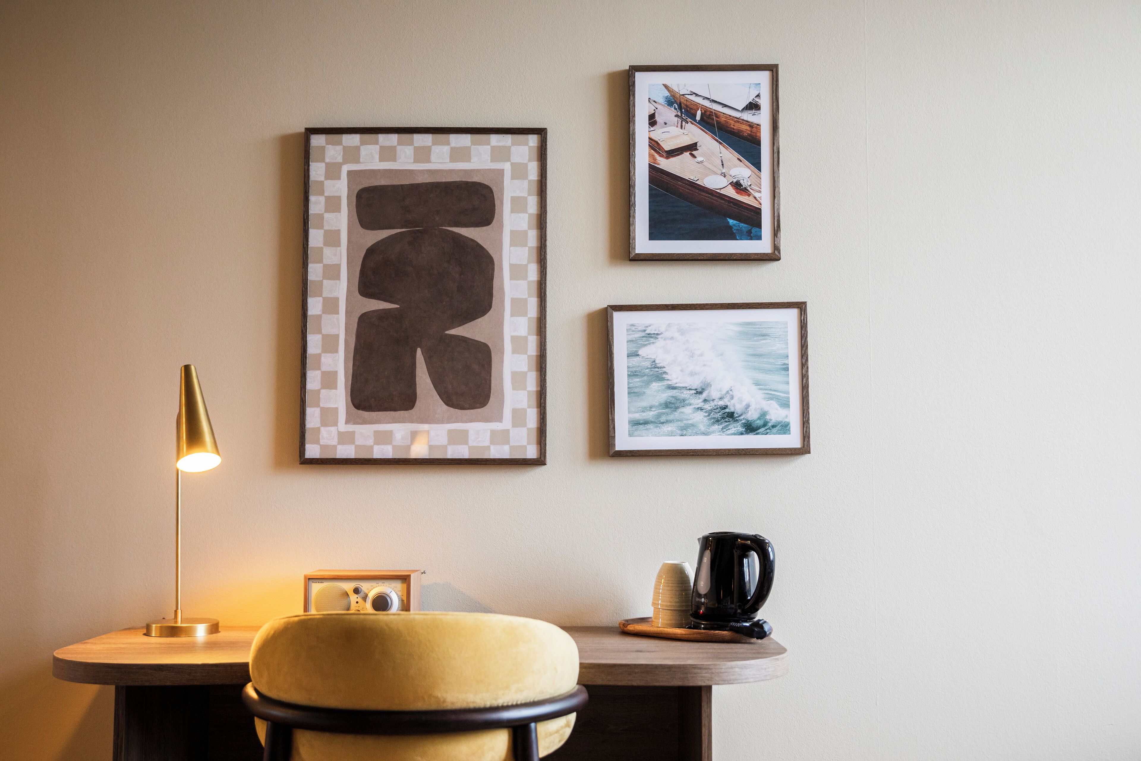 Una habitación con una mesa redonda, una silla amarilla, una lámpara y cuadros en la pared.