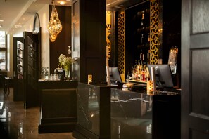 A bar area with a marble counter, a hanging light fixture, and a patterned wall.