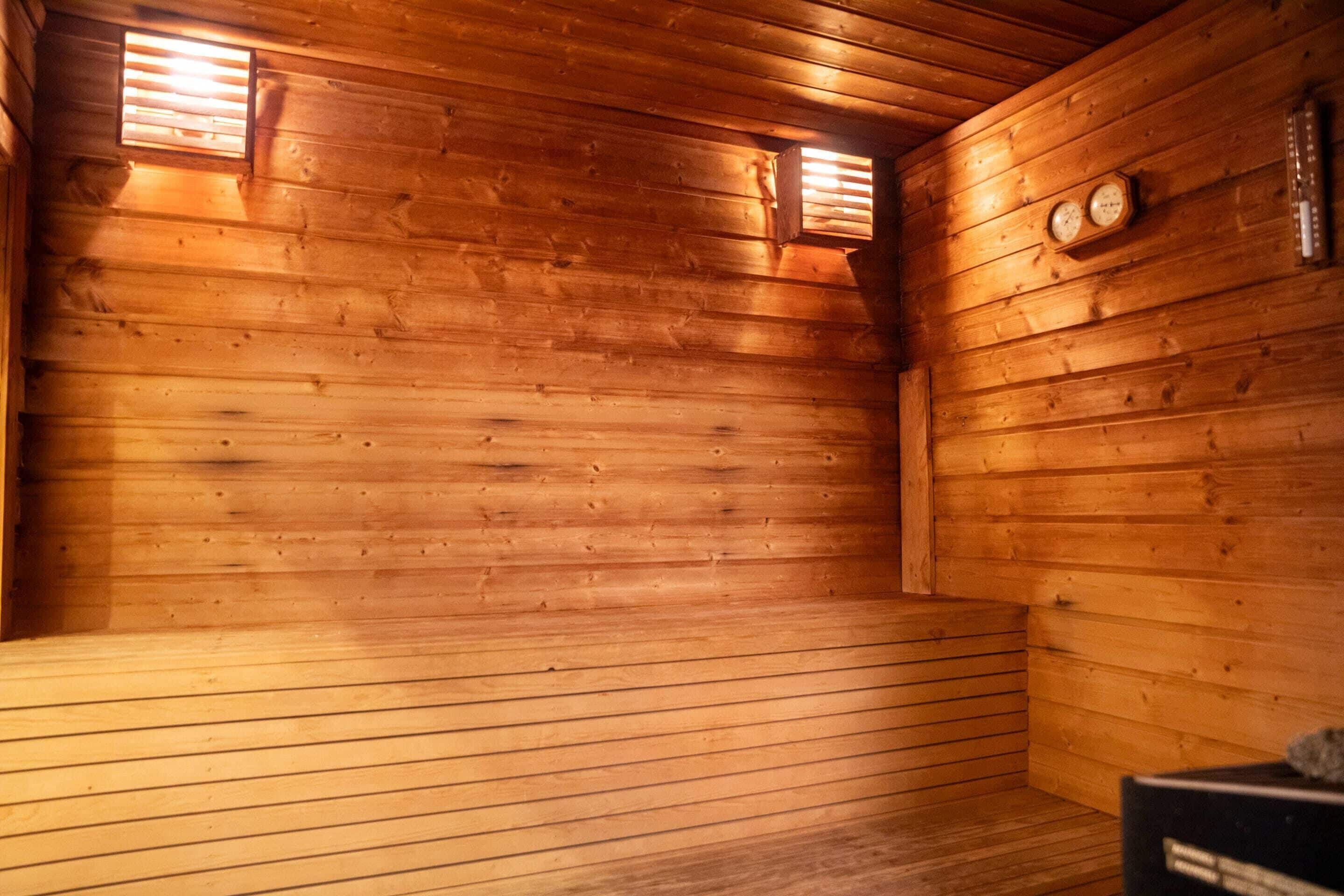A wooden cabin interior with a sloped ceiling, wooden walls, and a bench along one wall.