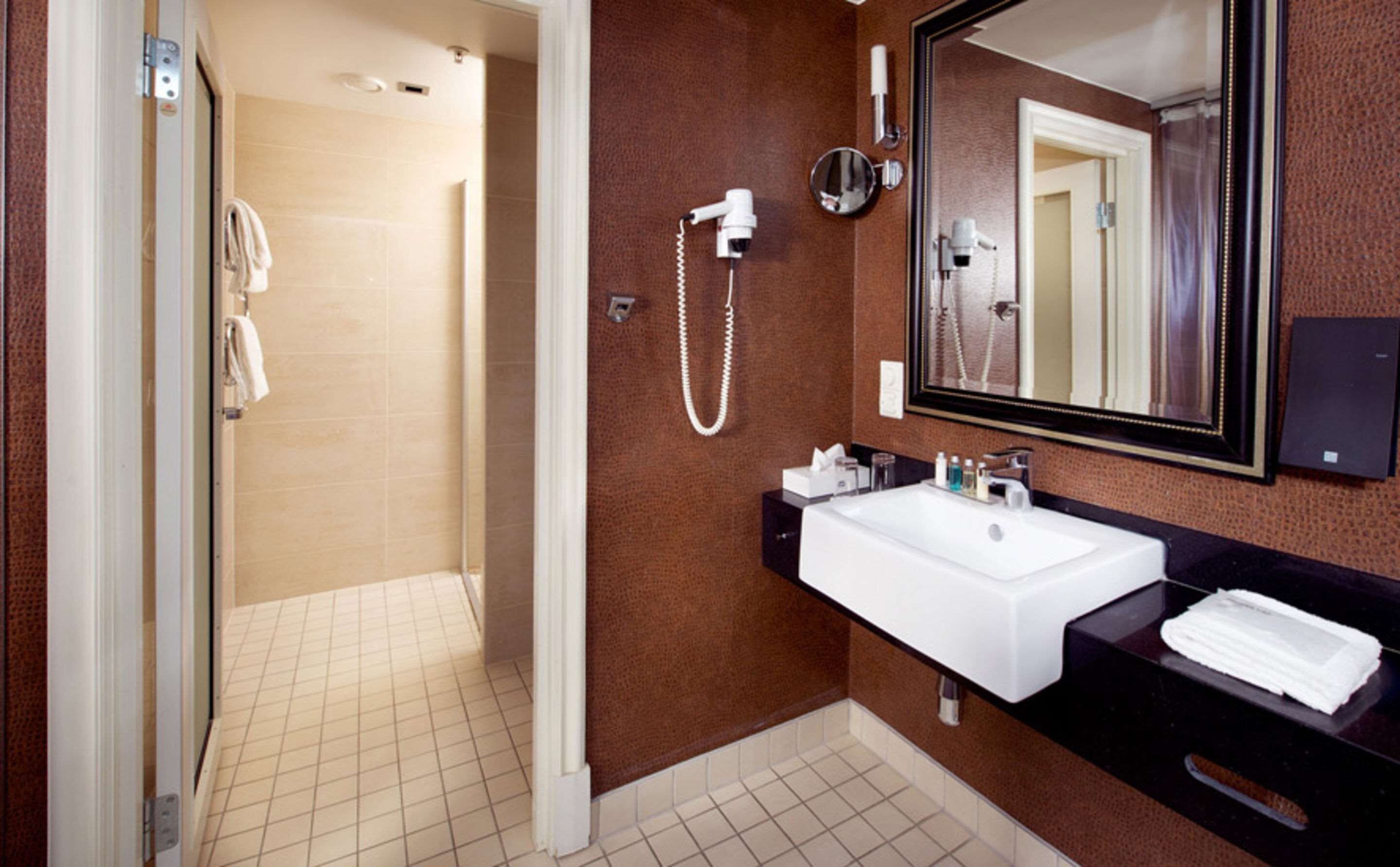 A bathroom with a white sink, a mirror, and a shower.