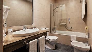 A bathroom with a sink, toilet, bidet, and a shower area.