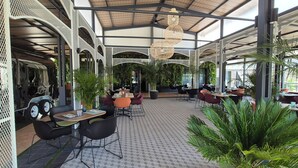 A spacious indoor area with tables and chairs, a patterned floor, and hanging lights. - Hotel Vértice Aljarafe (Bormujos)
