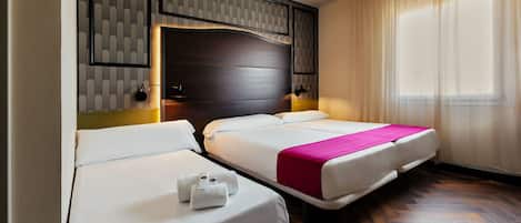 Una habitación de hotel con dos camas, cabecera de madera, un ventanal con cortinas translúcidas y suelo de madera.