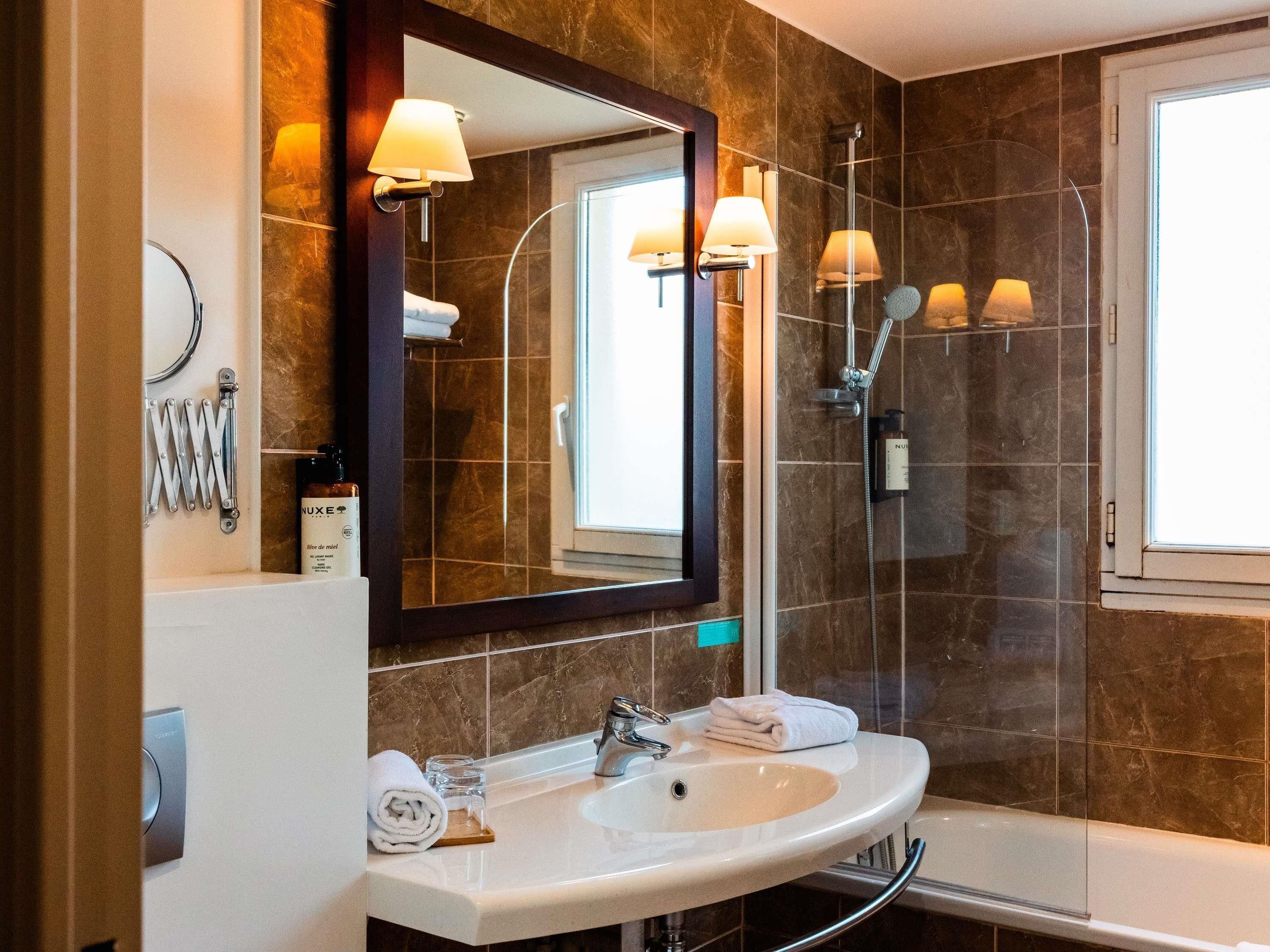 Un baño con lavabo, espejo, toallero y ducha.