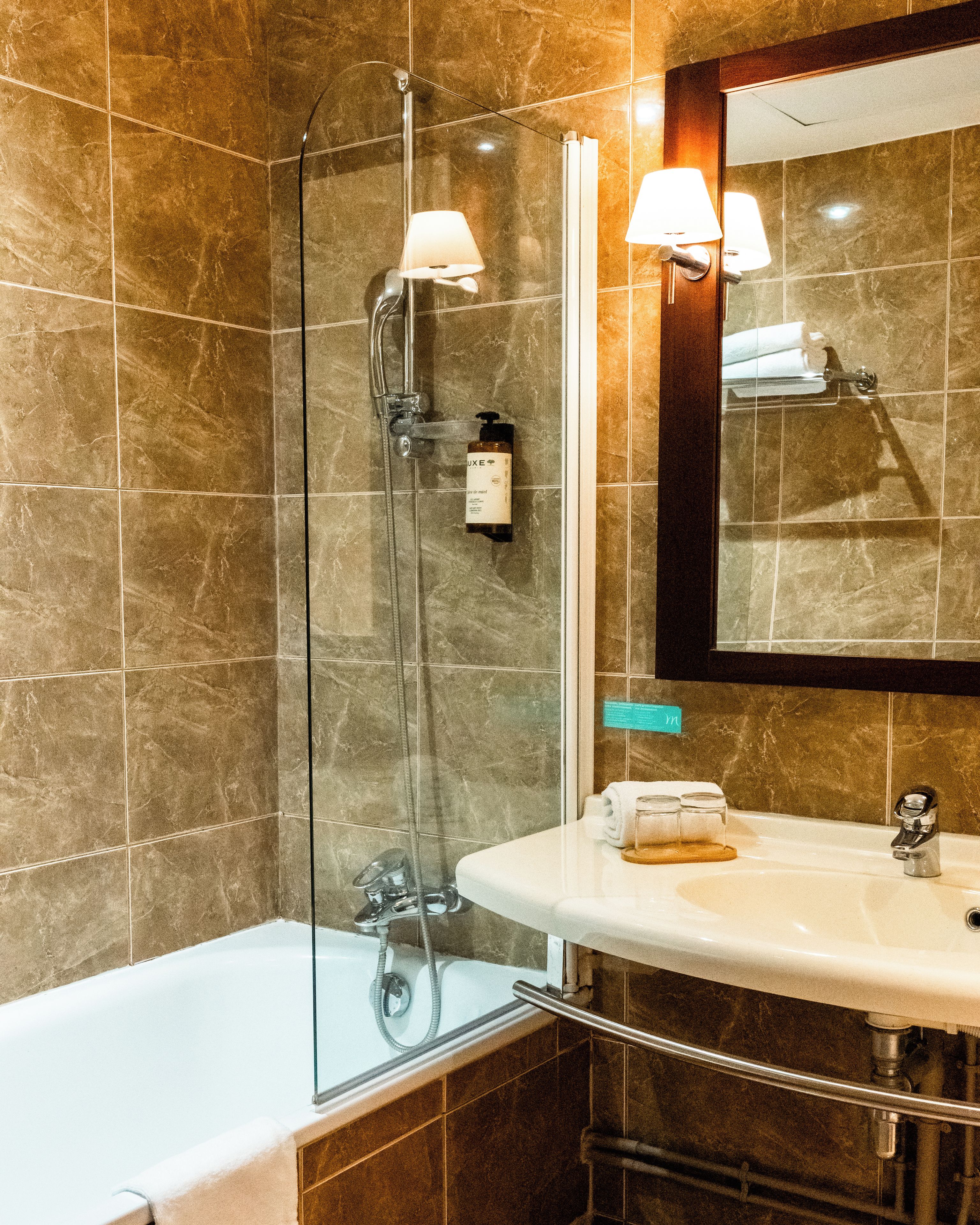 Une salle de bain avec une douche à parois de verre, un lavabo blanc et un miroir au-dessus du lavabo.