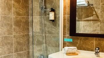 Une salle de bain avec une douche à parois de verre, un lavabo blanc et un miroir au-dessus du lavabo.