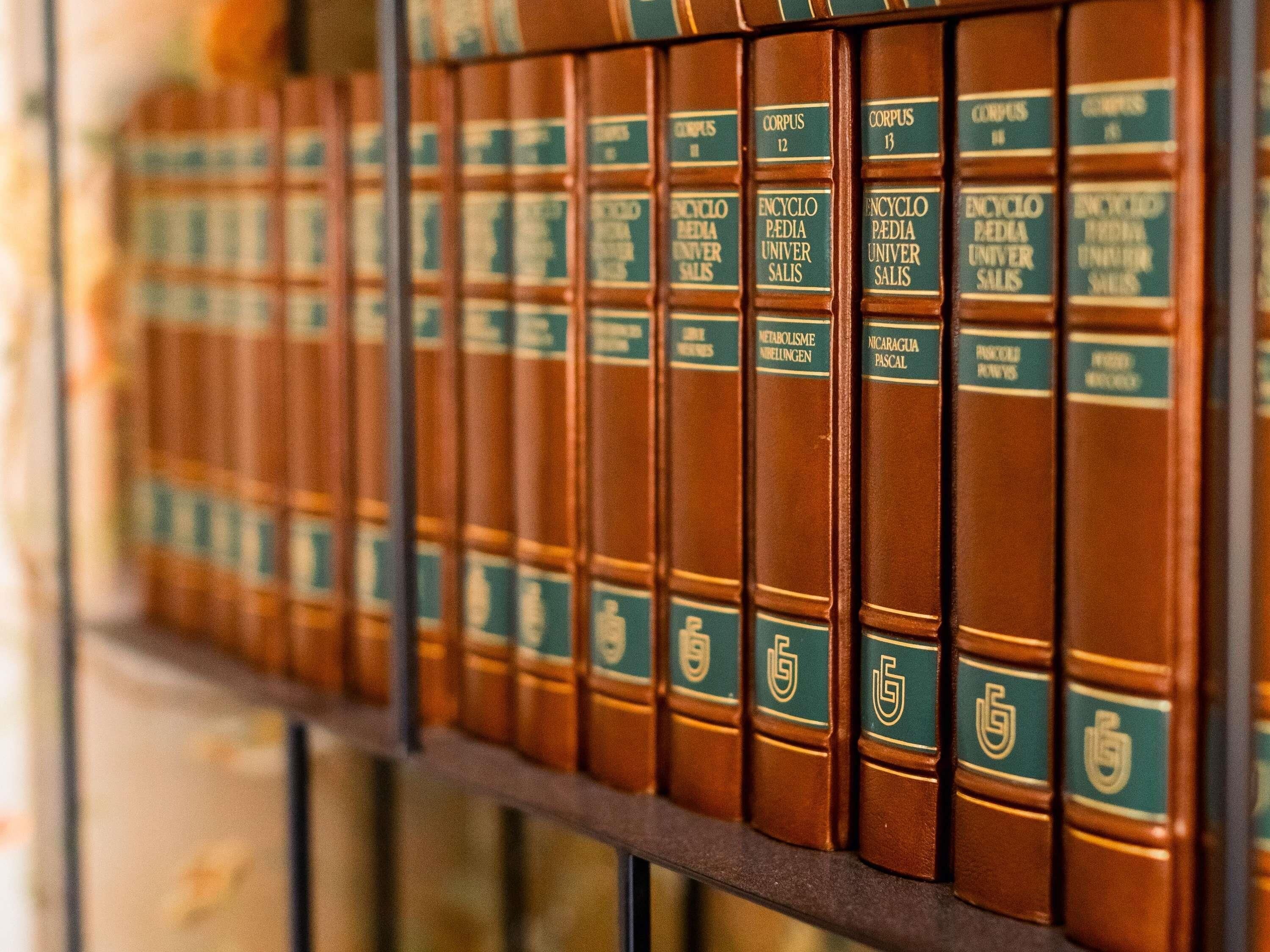 A row of leather-bound books with green labels, likely a collection of encyclopedias or reference materials.