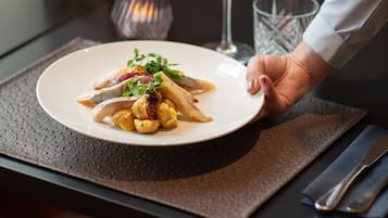 A dining table with a plate of food, a glass of wine, and a menu.