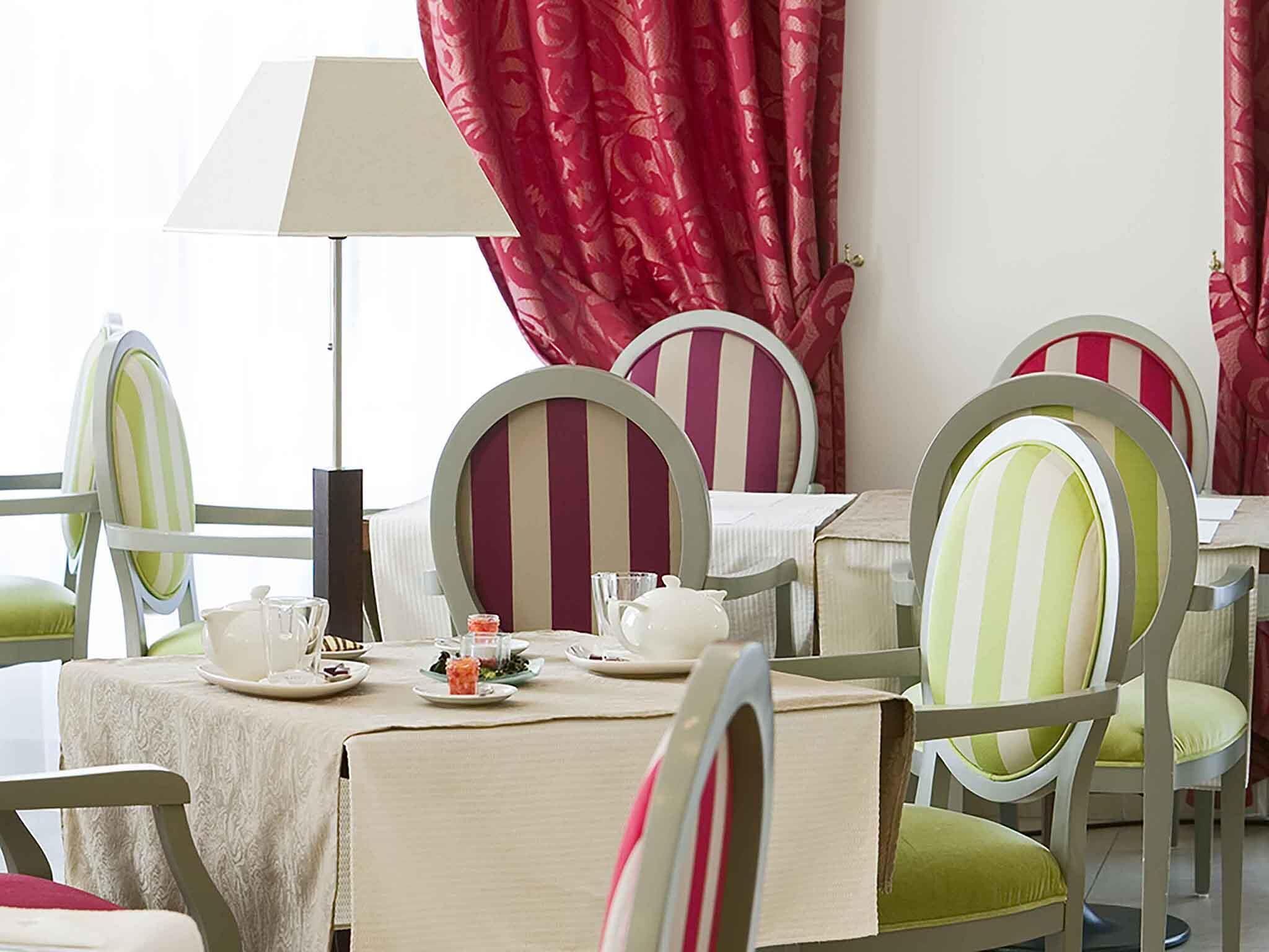 A dining area with striped chairs, a table set with plates, glasses, and a teapot.