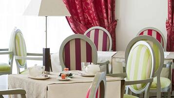 A dining area with striped chairs, a table set with plates, glasses, and a teapot.