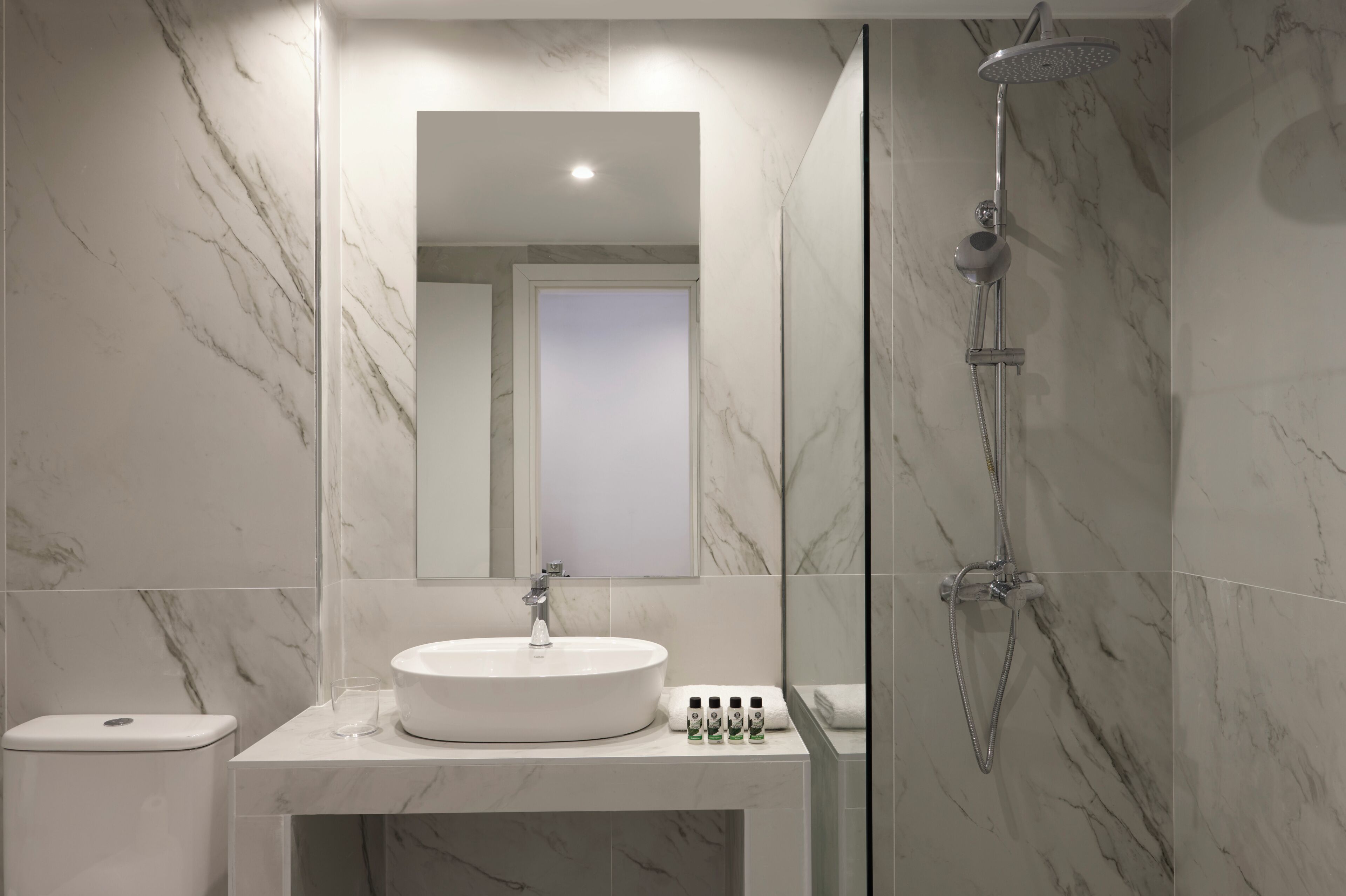 Et moderne badeværelse med en marmorvask, en brusekabine i glas og et toilet.